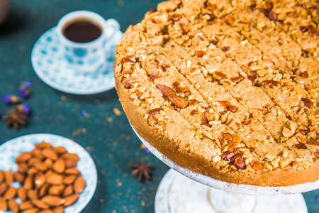 Cut cake on table with almonds and a cup of coffee. Baked dessert with chopped nuts in plate on table with coffee, piece of cake and almonds.の写真素材