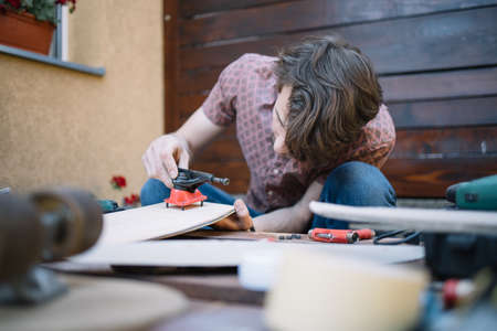 Concentrated man putting skateboard truck on deck. Focused man assembling skateboard parts in...