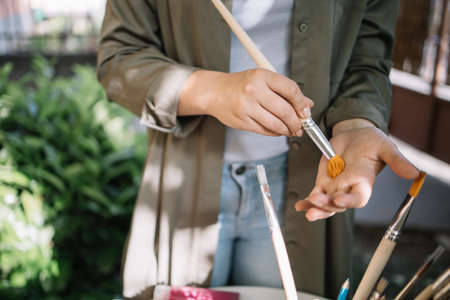 Close-up view of hands rubbing new brush. Portrait of female hands rubbing new paint brush on hand in nature.の写真素材