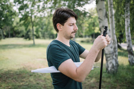 Side view of man setting up umbrella stand. Photographer setting equipment for taking outdoor photo session and holding umbrella.の写真素材