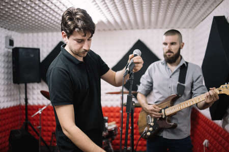 Rock music band ready for repetition in soundproof room. Music band members ready to perform and...