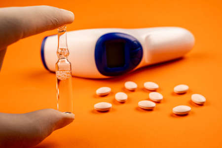 Hand with latex glove holding medicine ampoule. Close-up view of hand with protective gloves holding...