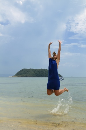Girl trying to reach the sky over the water in Koh Pagnan island, Thailandの写真素材