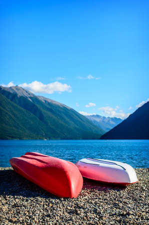 A beautiful recreation area with a couple colorful kayaks on shore lakeの写真素材