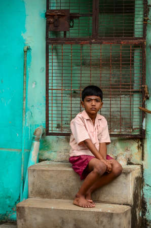 TRICHY,  INDIA - FEBRUARY 15: Unidentified Indian boy sitting near colorful wall of his house at street on February 15, 2012. India, Trichy, Tamil Naduのeditorial素材