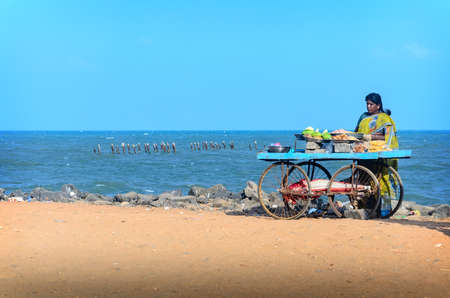 PONDICHERRY, INDIA - FEBRUARY 2, 2013: Unidentified Indian street vendor of  snacks with wheel cart on beachのeditorial素材