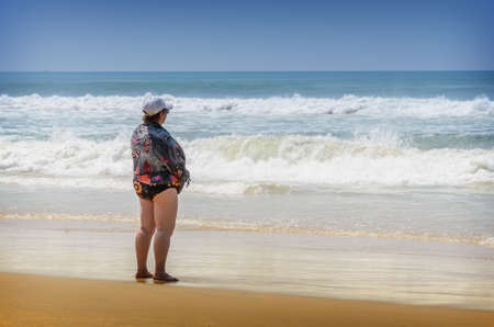 Fat lonely woman standing on the beach in Varkala, Indiaのeditorial素材