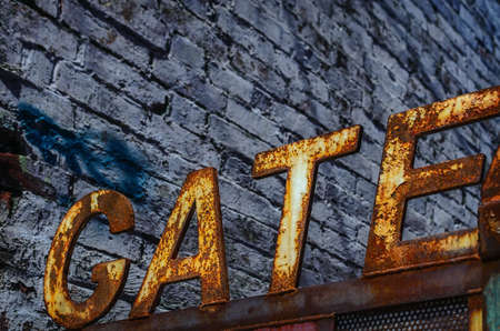 A door with rusty sign \"GATE\"  on brick wall backgroundの写真素材