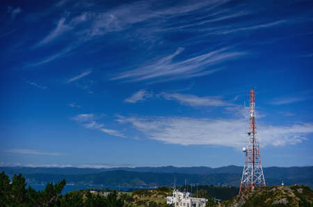 Red and white tele-radio tower against a background of the blue sky.の写真素材