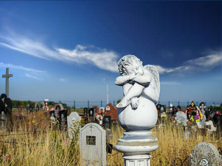 Dreaming Angel on the ball at cemetery against blue skyの写真素材