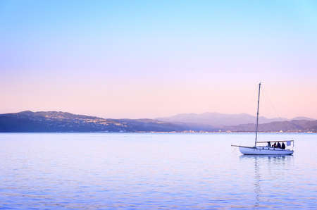 People enjoy the sunset on a sailboat in the ocean harbor in Wellington, New zealand