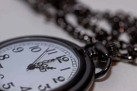Closeup of a vintage black pocket watch on white surfaceの写真素材