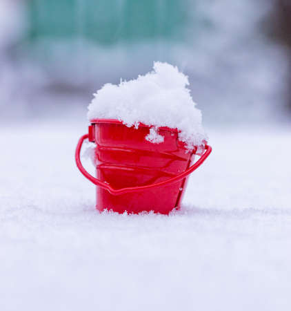 Closeup of a red mini bucket filled with snowの写真素材