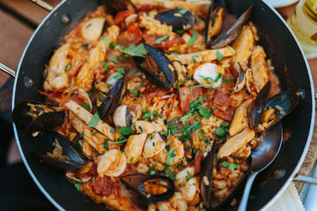 Classic dish of Spain, seafood paella in traditional pan on rustic wooden background top view....