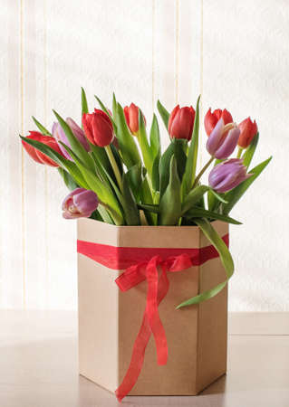 Lilac tulips on a table in a glass vase on a sunny day, a gift from a loved oneの写真素材