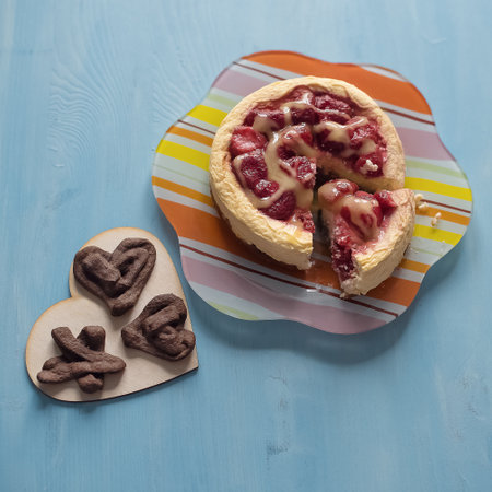 Curd diet cake with strawberries and creamy sauce on a striped plate and linen cookies on a heart-shaped plate. Homemade food, healthy food.の写真素材