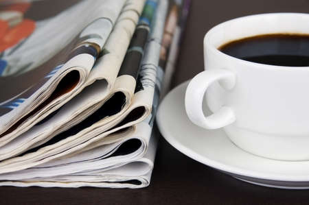 Pile of newspapers and cup of coffee on the table