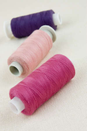 Three multicolored thread spools on textile background