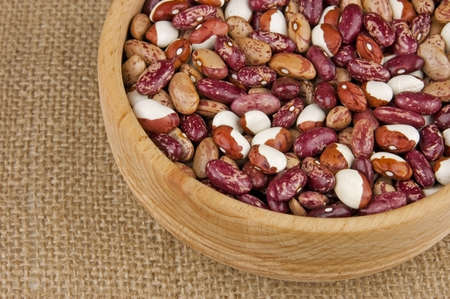 Multicolored pinto kidney beans mix in wooden bowl close up