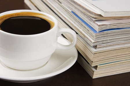 Pile of magazines and cup of coffee on tableの写真素材