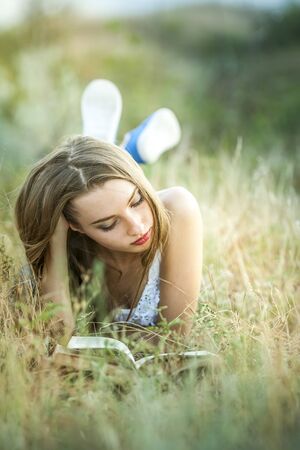 a girl reading a book outsideの写真素材