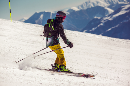 Skier on piste running downhill in beautiful Alpine landscape. Blue sky on background. Free space for textの写真素材