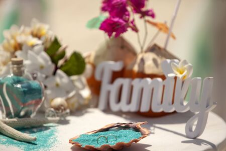 Accessory kit for a wedding on the beach. Decorated coconuts, bridal bouquet with neroli, certificate of marriage and shell for rings on the table. Wedding decor for tropical sand ceremony on the beach, Maldives. Wedding and honeymoon concept.の写真素材