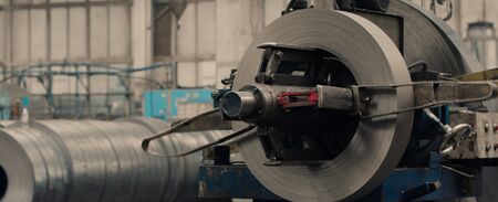 Industrial tiered rack with sheet metal rolls for metal profile forming machine in metalwork factory workshop. Concept for metalwork production. Close up.の写真素材