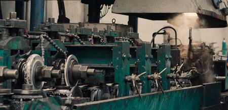 Industrial steel roll coil for metal profile forming machine in metalwork factory workshop. Sprockets , steel cog gear set, high precision metal sheet bending machine. Concept for metalwork production. Close up. Selective focus.の写真素材