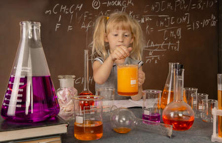 Curious little girl with test tubes and colorful substances makes tests at school laboratory. Small kid learning chemistry and conducts science experiment on biology lesson. Future microbiologist.の写真素材