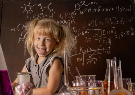Curious little girl with test tubes and colorful substances makes tests at school laboratory. Small kid learning chemistry and conducts science experiment on biology lesson. Future microbiologist.の写真素材