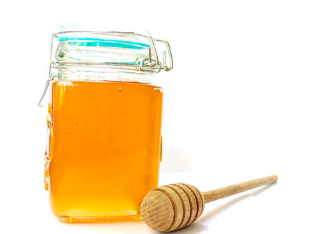 Glass jar of floral golden honey with lid wooden honey stick space for text