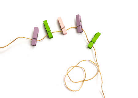Multicolored wooden clothespins lies on a rope isolated on white background view from above