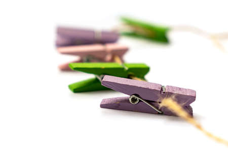Multicolored wooden clothespins lies on a rope isolated on white backgroundの写真素材