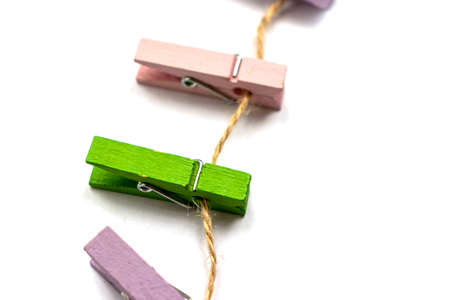 Multicolored wooden clothespins lies on a rope isolated on white background view from aboveの写真素材