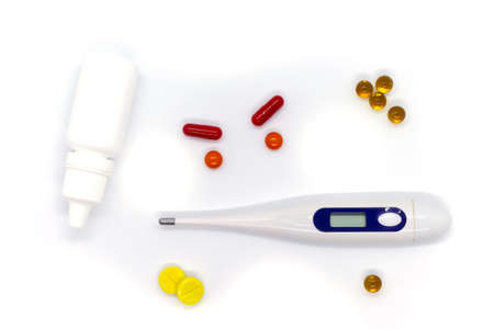 Medical electronic thermometer, medicine, drops and pills on white background. Top view.
