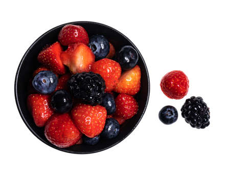 Detailed top view of 3 sorts of fruit in black round bowl, isolated on a white backgroundの写真素材