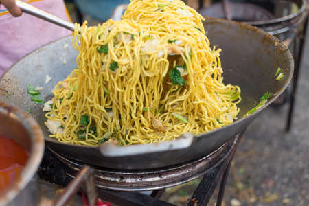 Yellow noodles with vegetable cooking on pan in Vegetarian Festival Thailandの写真素材