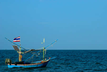Thai fishing boat used as a vehicle for finding fish in the sea at sunsetの写真素材