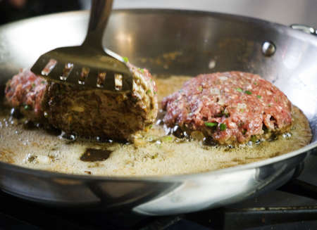 Spatula Lifting Gourmet Burger in Frying Panの写真素材