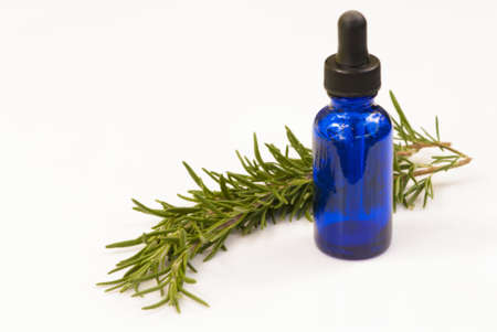 Sprig of Fresh Rosemary next to blue medicine bottle on white backgroundの写真素材