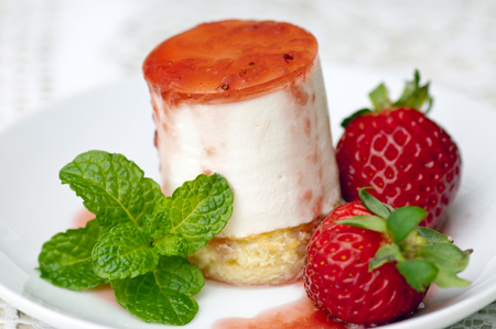 A strawberry cheese cake with fresh strawberries and a mint garnishの写真素材