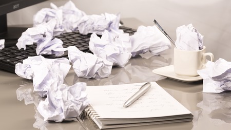 Office workplace with book, crumpled paper, pen,  on grey deskの写真素材