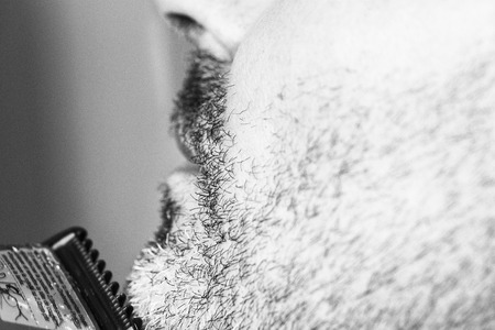Hairdresser, cutting beard of his customer with scissors and shave in the salonの写真素材