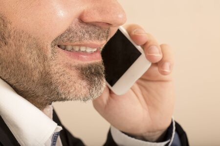 Close up of attractive man talking on the telephone white background