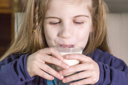 Close-up portrait of beautiful smiling little girl having breakfast, food and drink concept, healthy food, indoorの写真素材