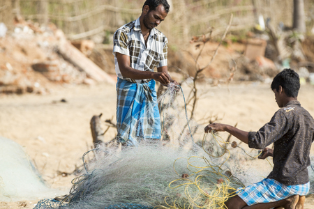 Pondichery, Tamil Nadu, India - February 27, 2014 : Traditional fishermen on beach, on sea, on sand. Long boats, Hard work poor peopleのeditorial素材