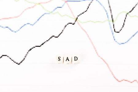 Sad written with wood cubes letters on financial business graph
