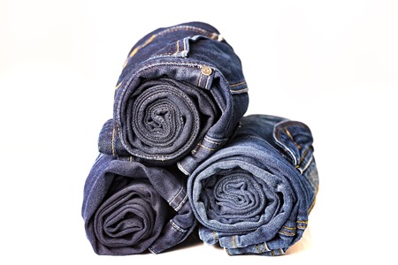 Pile of ree different blue jeans on white tableの写真素材