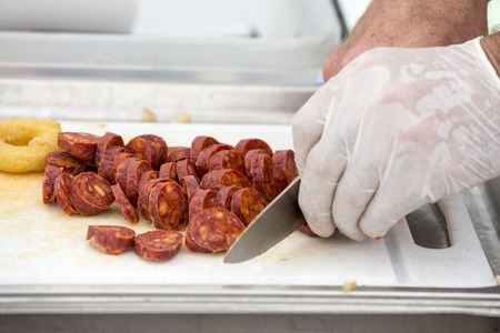 Cooker cutting chorizo sausage pepperoni on white tableの写真素材